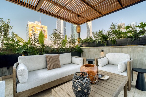 A rooftop terrace with a sofa, chairs, a coffee table, and decorative items. - Rooftop - in Roma Norte (Mexico City)