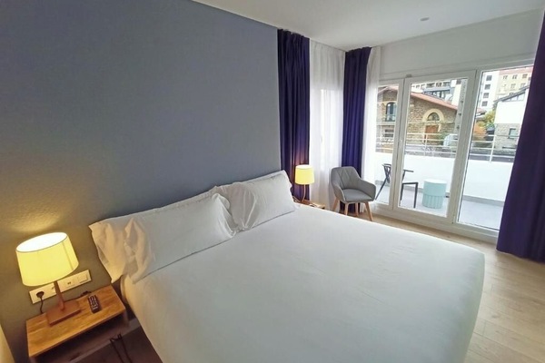 Unwind in a sunlit king bed with balcony breeze.