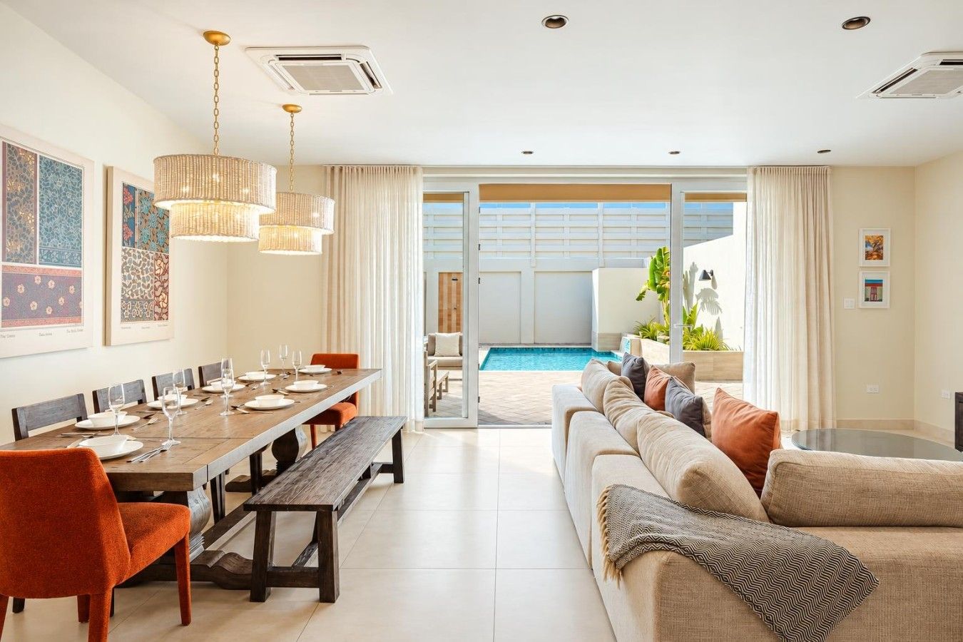 A modern living room with a dining area, a pool, and a sofa with cushions.