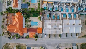 Eine Luftaufnahme eines Hotels mit mehreren Schwimmbecken, einem Dachgarten und einem Parkplatz.