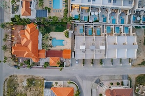 Vista aérea de un hotel con múltiples piscinas, un jardín en la azotea y un estacionamiento.