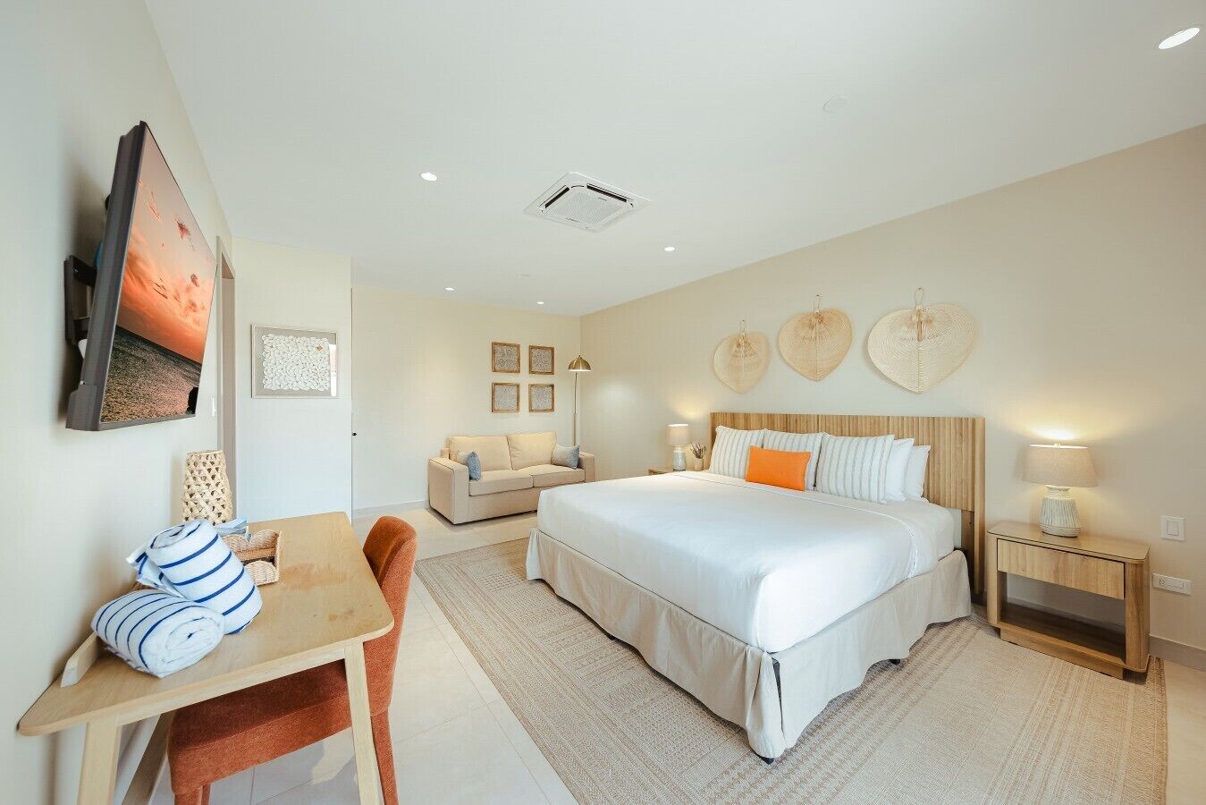 Habitación de hotel con cama, escritorio, sillón, sofá y televisor.