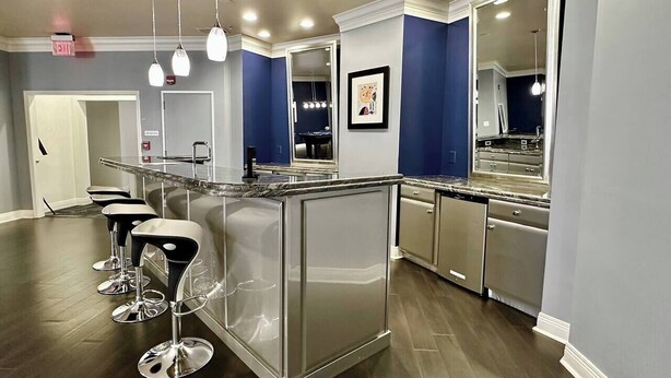 Une cuisine moderne dotée d’un îlot central, de tabourets de bar, d’appareils électroménagers en acier inoxydable et de murs d’accent bleu.