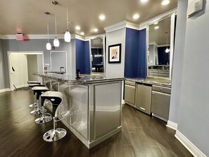 A modern kitchen with a central island, bar stools, stainless steel appliances, and blue accent walls.