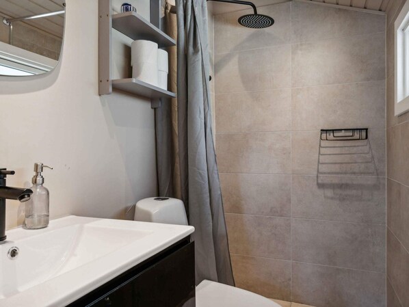 A modern bathroom with a shower, a sink, and a toilet. - 5 Star Holiday Home in Hals (Hals)