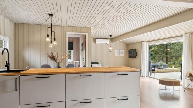 A modern kitchen with a wooden countertop, white cabinets, and pendant lighting. - 5 Star Holiday Home in Hals (Hals)