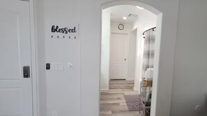 A hallway with a white door, a sign reading "blessed," and a clock on the wall. - The Pool House at East Mesa close to Superstition Mountain, Goldfield Ghost town (Mesa)
