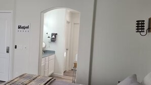 A bedroom with a bed, a door, a hallway leading to a bathroom, and a wall with a 'blessed' sign. - The Pool House at East Mesa close to Superstition Mountain, Goldfield Ghost town (Mesa)