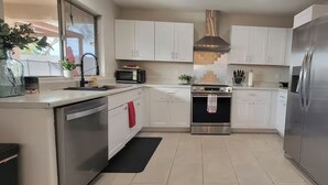 A modern kitchen with white cabinets, stainless steel appliances, and a black countertop. - The Pool House at East Mesa close to Superstition Mountain, Goldfield Ghost town (Mesa)