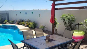 A covered patio with a pool, outdoor table and chairs, and a red umbrella. - The Pool House at East Mesa close to Superstition Mountain, Goldfield Ghost town (Mesa)