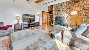 Ein Wohnzimmer mit Steinwand, Kamin, Sofa, Couchtisch und Bücherregal.