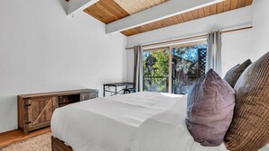 Ein Schlafzimmer mit einem großen Bett, einem Holzkopfstück, einem Schreibtisch und einem Fenster mit Vorhängen.