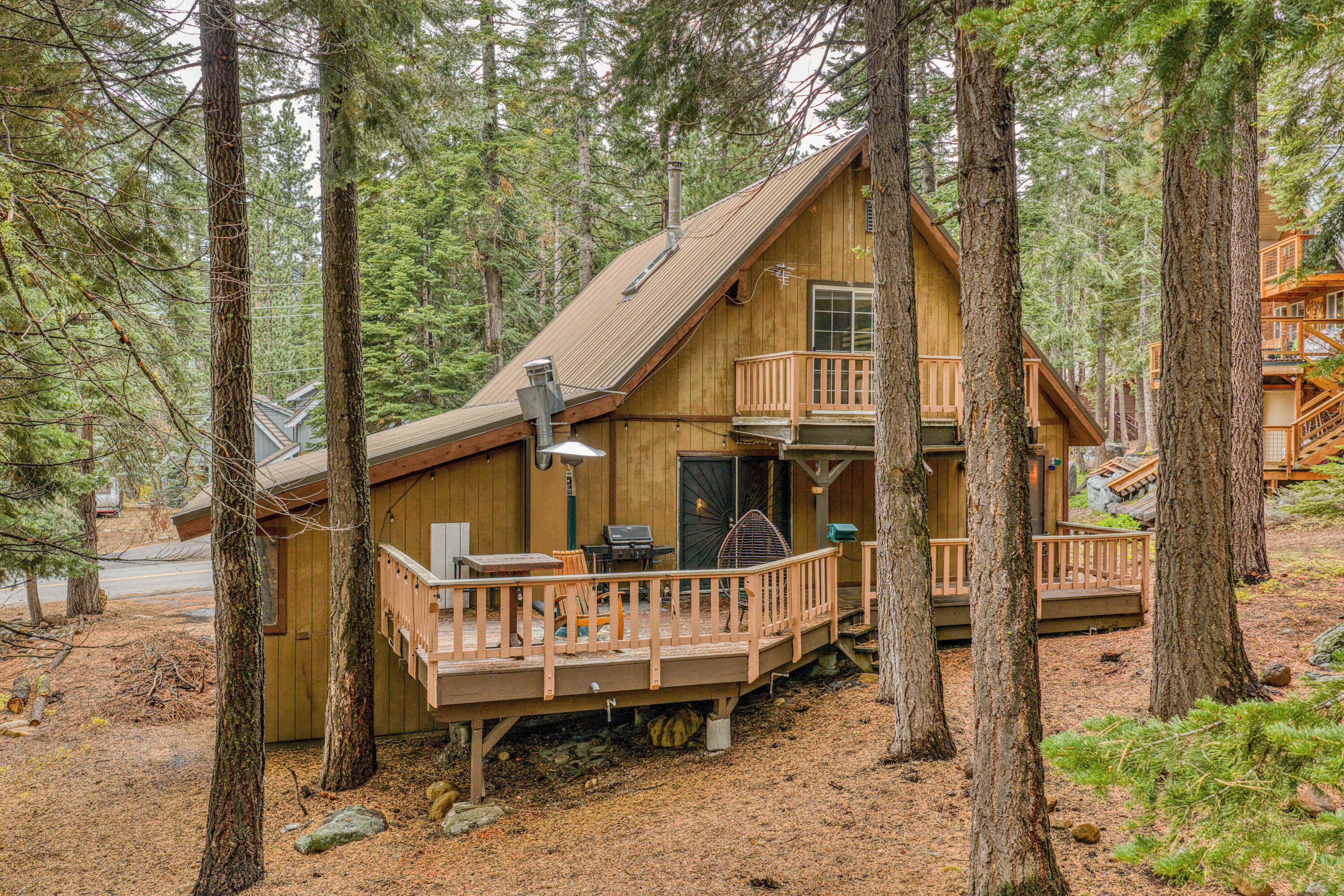 A cabin with a deck, a grill, and a large window.