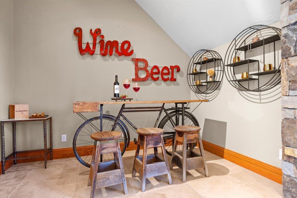 Una habitación con un cartel en la pared que dice 'Vino Cerveza', una bicicleta y una mesa de madera con taburetes.