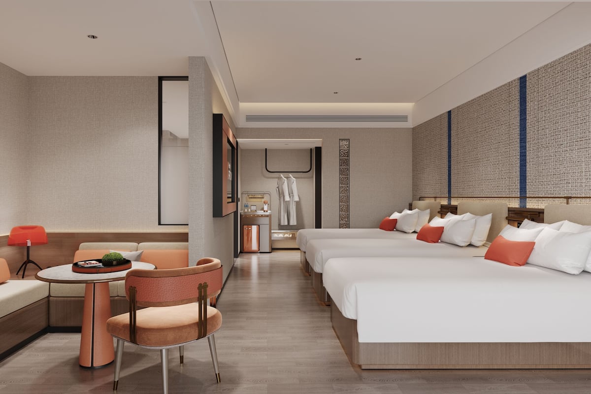 Ein Hotelzimmer mit einer Couch, einem Esstisch, einem Stuhl und einem Bett mit vielen Kissen.