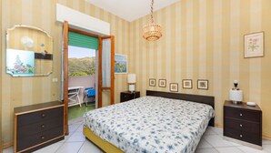 Une chambre à coucher comprenant un lit, des tables de chevet, une commode, un miroir et une vue sur l’extérieur.