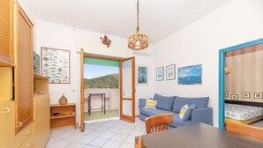 Une pièce avec une armoire en bois, un canapé, une table à manger et une vue sur l’extérieur.