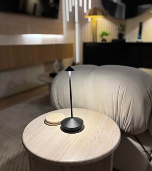 Ein runder Holztisch mit einer schwarzen Lampe, einem weißen Kissen und einem kleinen Holzgegenstand darauf.