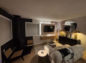 A modern living room with a sofa, armchair, and a TV mounted on the wall.