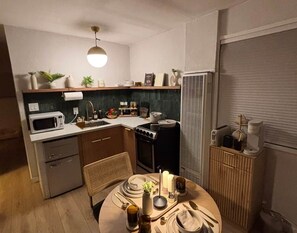 A compact kitchen with a dining area, equipped with a microwave, stove, and refrigerator.