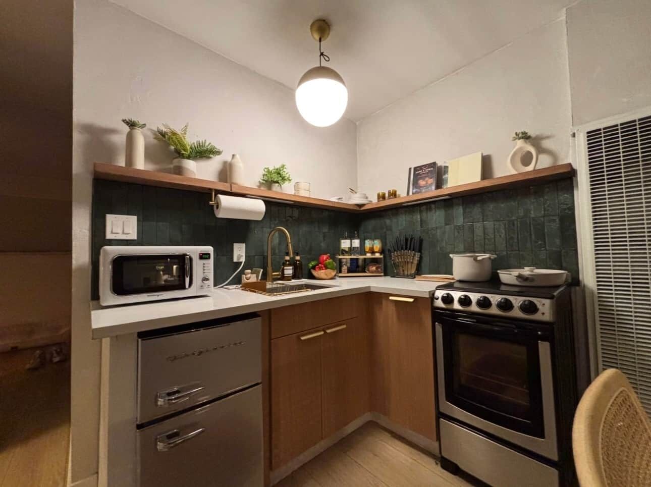 A compact kitchen with a microwave, stove, sink, and wooden cabinets.
