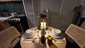A round dining table with two chairs, a vase with a plant, and a candle. - Black Diamond Retreat Designer Cabin Hot Tub (Big Bear)