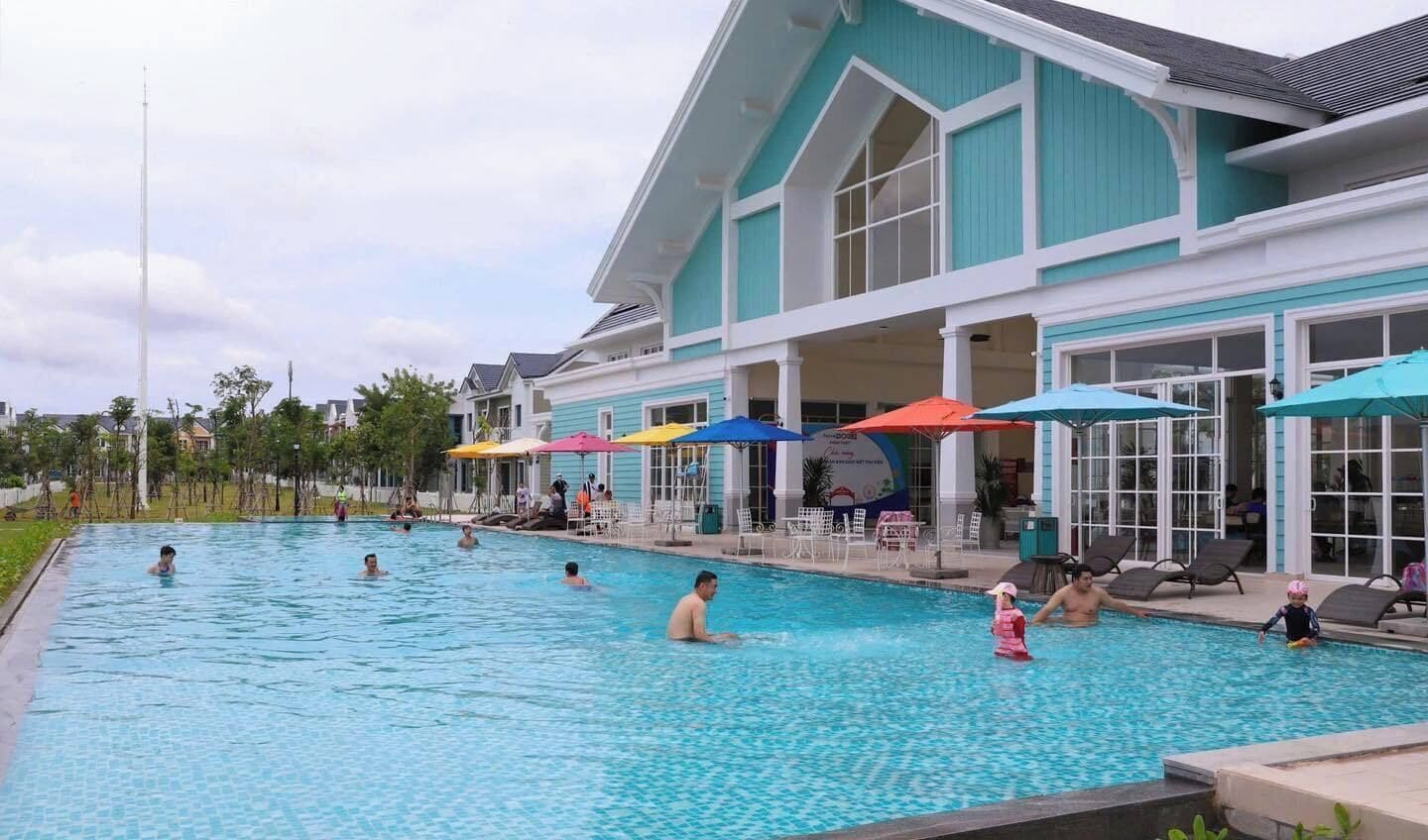 A swimming pool area with lounge chairs and umbrellas, surrounded by a building with large windows.