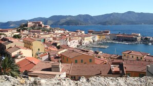 A coastal town with historic buildings, a marina, and mountains in the background. - Appartamento Lentisco - Lentisco (Portoferraio)