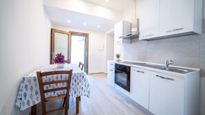 A modern kitchen with white cabinets, a stainless steel sink, and a built-in oven. - Appartamento Lentisco - Lentisco (Portoferraio)