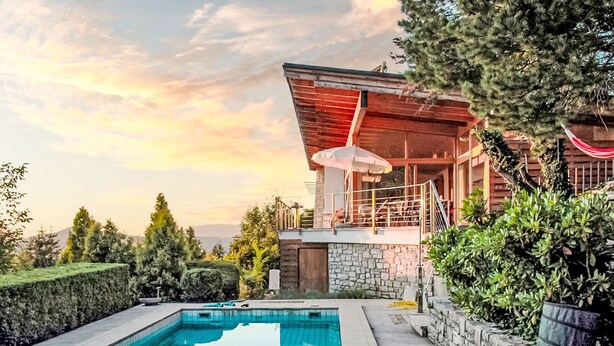 Uma casa moderna com piscina, paredes de pedra e área de varanda.
