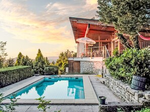 Une maison moderne dotée d’une piscine, de murs en pierre et d’un espace patio.