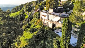 Uma casa moderna com piscina, rodeada por vegetação exuberante e colinas.