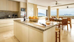 Une cuisine moderne dotée d’un grand îlot central, d’un coin repas offrant une belle vue et d’un ventilateur de plafond.