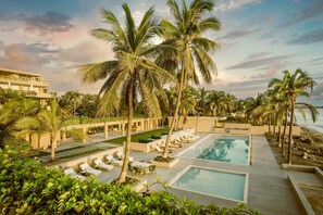 A resort with multiple swimming pools, palm trees, and lounge areas.