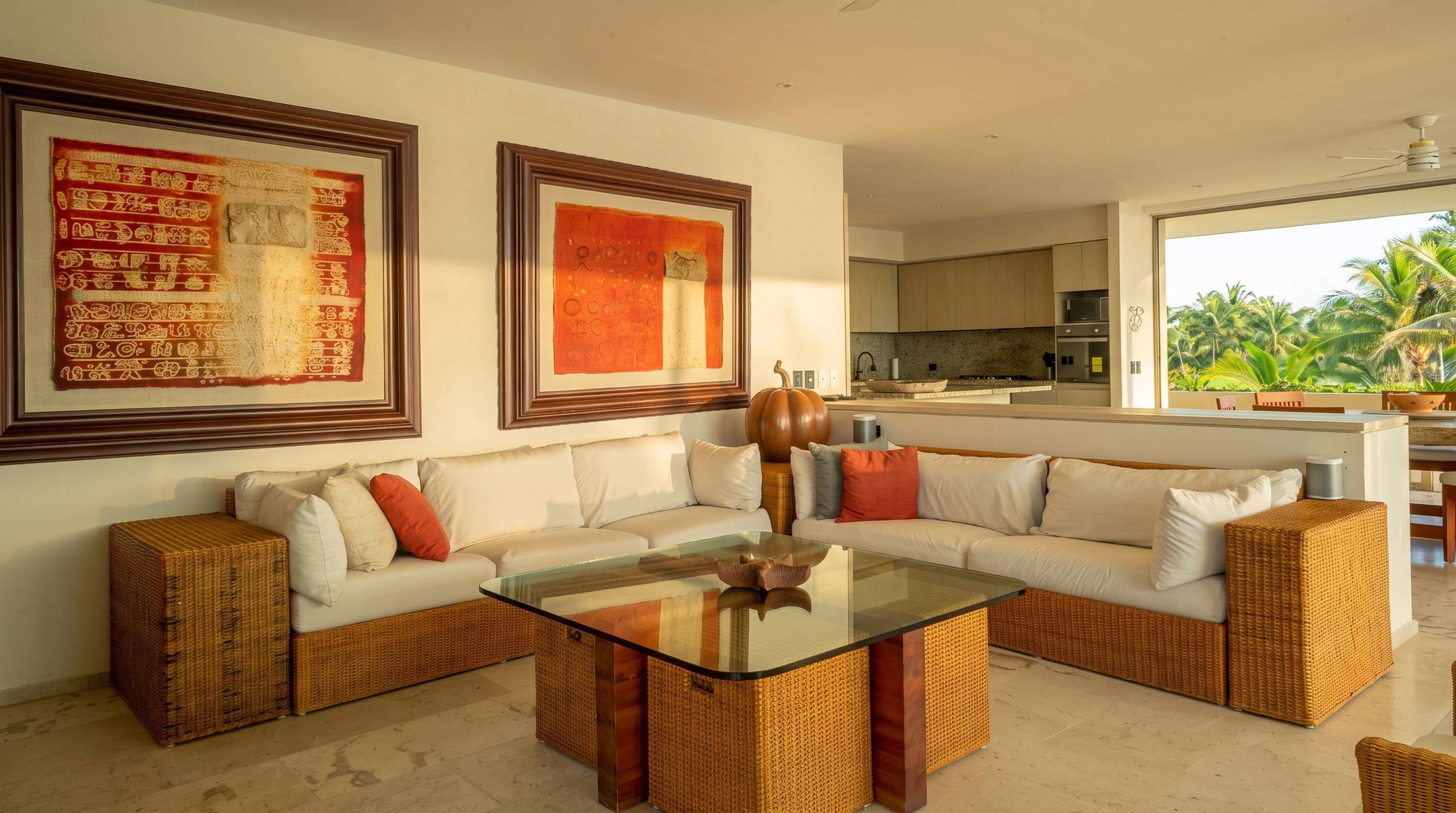 A modern living room with a glass coffee table, a sofa set, and two framed artworks on the wall.