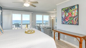 Ein Schlafzimmer mit einem großen Bett, einem Deckenventilator, Blick auf den Ozean und einem Bild an der Wand.