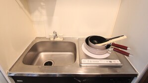 A stainless steel sink with a faucet, a scale, and a bowl with two wooden-handled utensils on a countertop. - Small-Town Feel, Big-City Access | Homey Stay in Nakano (中野区野方)