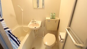 A small bathroom with a bathtub, sink, toilet, and two bottles of shampoo on the toilet tank. - Small-Town Feel, Big-City Access | Homey Stay in Nakano (中野区野方)