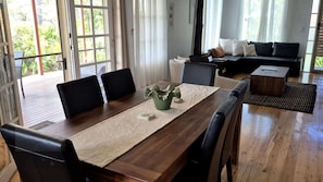 Un salon moderne avec une table à manger en bois, des chaises en cuir noir, un canapé et une table basse.