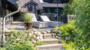 Eine Terrasse mit Gartenmöbeln, einer Steinmauer und einem großen Sonnenschirm.