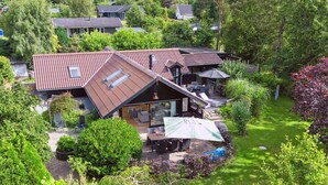 Ein Haus mit Schrägdach, einer Terrasse mit Gartenmöbeln und einem gepflegten Garten.