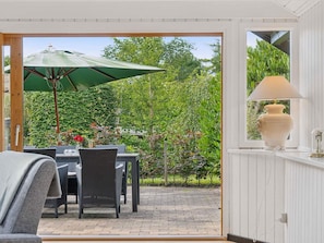 An outdoor patio with wicker furniture, a green umbrella, and a white lamp. - 5 Star Holiday Home in Nykobing Sj (Nykobing Sjaelland)