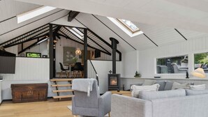Ein geräumiges Loft mit hohen Decken, freiliegenden Balken, einem Kamin und einer gemütlichen Sitzecke.