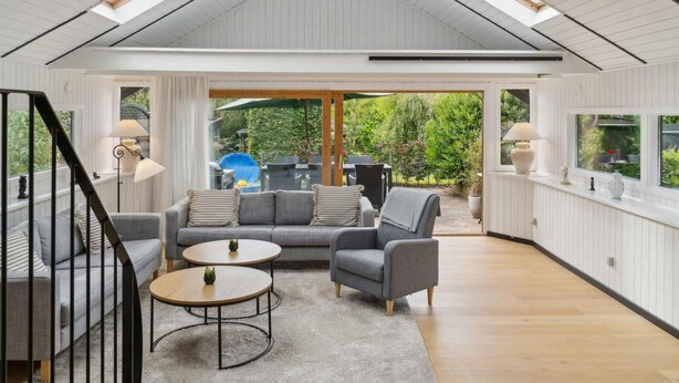 Ein modernes Wohnzimmer mit hohen Decken, großen Fenstern und Blick auf den Garten.