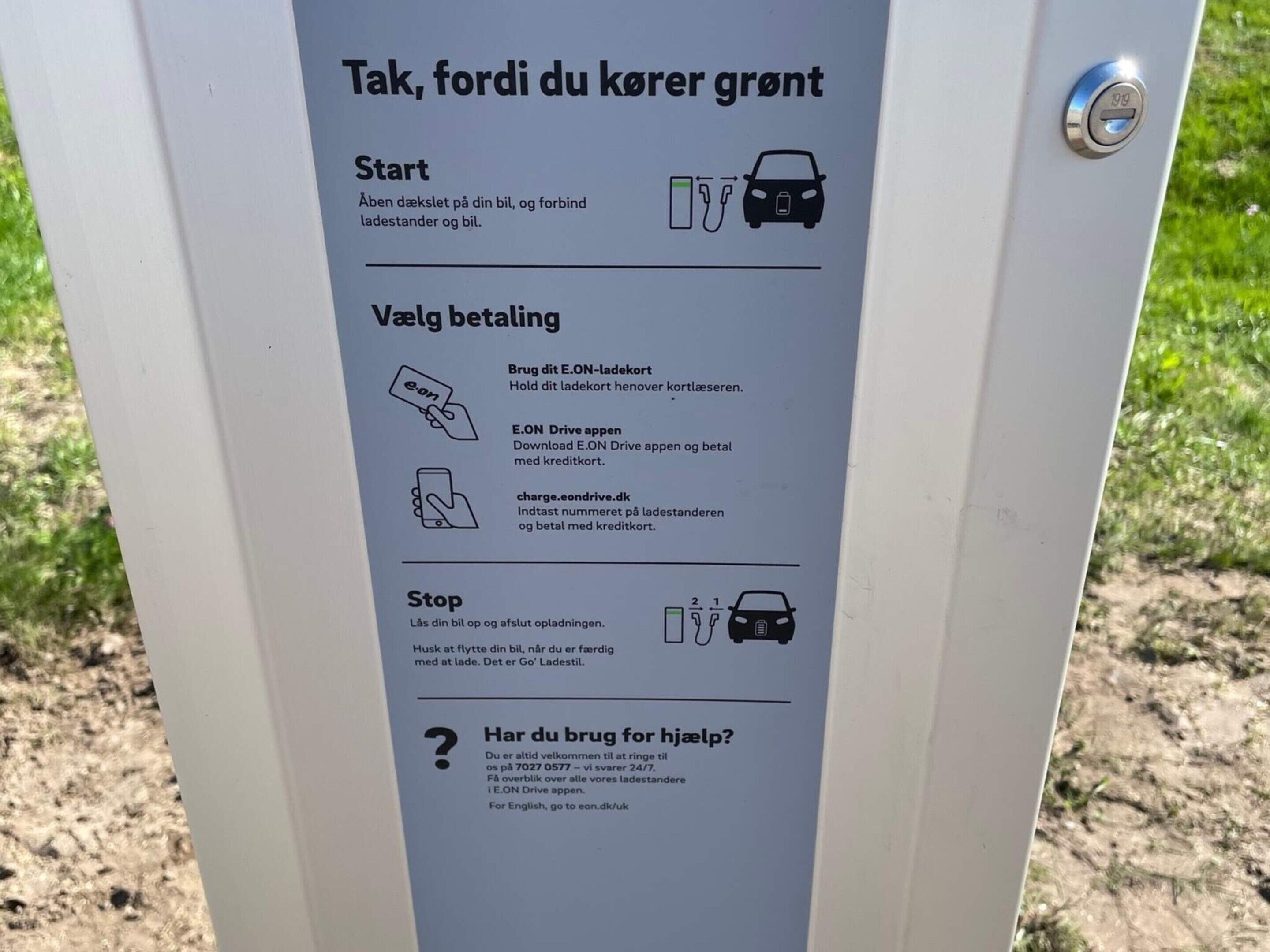 A charging station with instructions in Danish for starting, paying, and stopping the charging process.