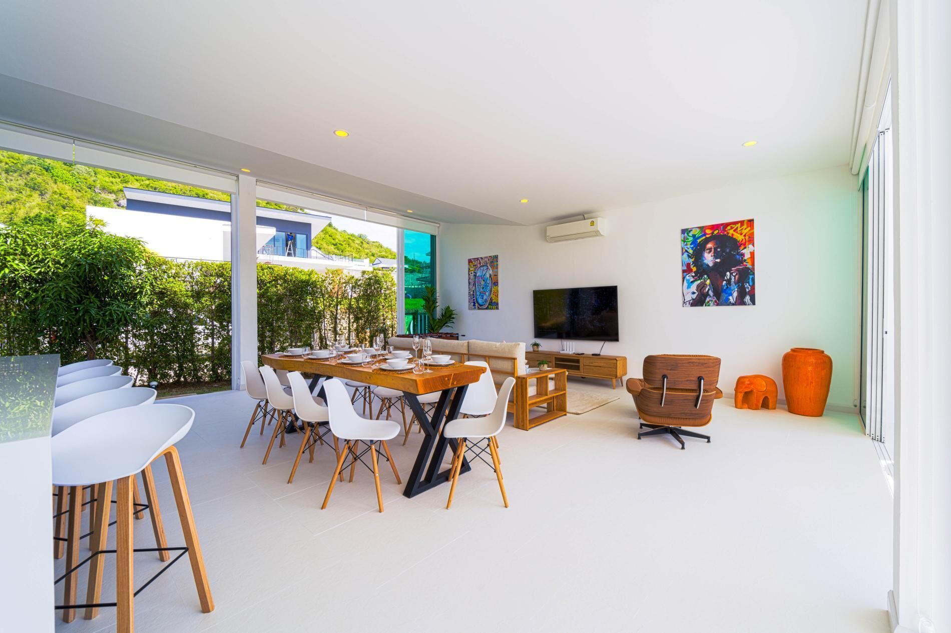 A modern living room with a dining area, large windows, and artwork on the walls.