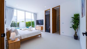 Une chambre moderne avec un grand lit, des lampes de chevet, une télévision et une vue sur une piscine.