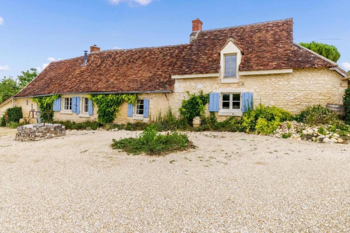A stone house with a gravel driveway and a small garden area.