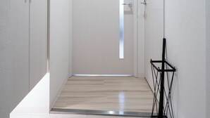 A narrow hallway with a door at the end, a small step leading to a higher floor, and a black metal rack against the wall. - EVARIA (Sapporo)