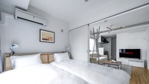 A modern hotel room with a large bed, a flat-screen TV, and a sliding glass door leading to a bathroom. - EVARIA (Sapporo)